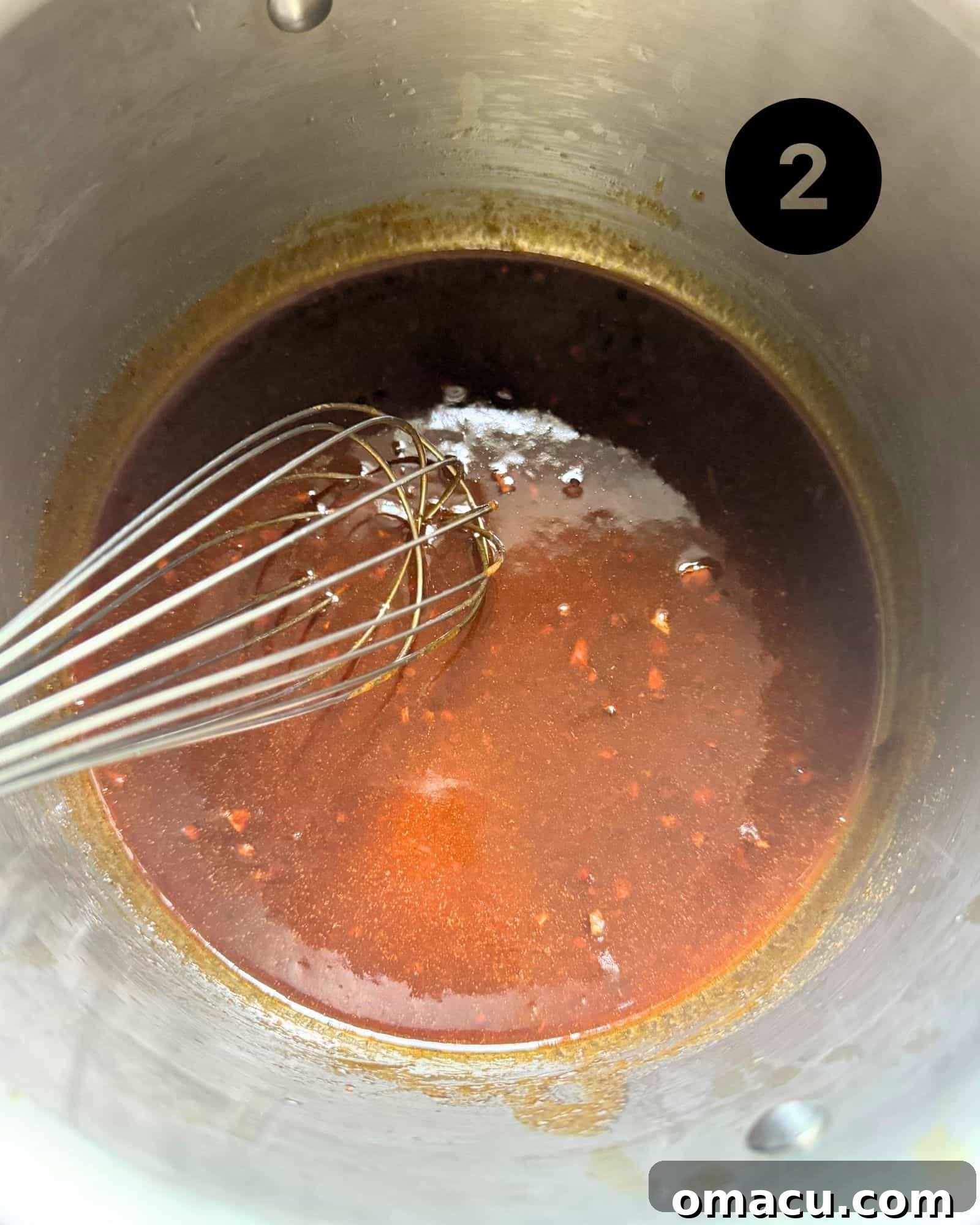 Cajun Honey Butter Sauce simmering in a saucepan, showing its rich, thick texture.