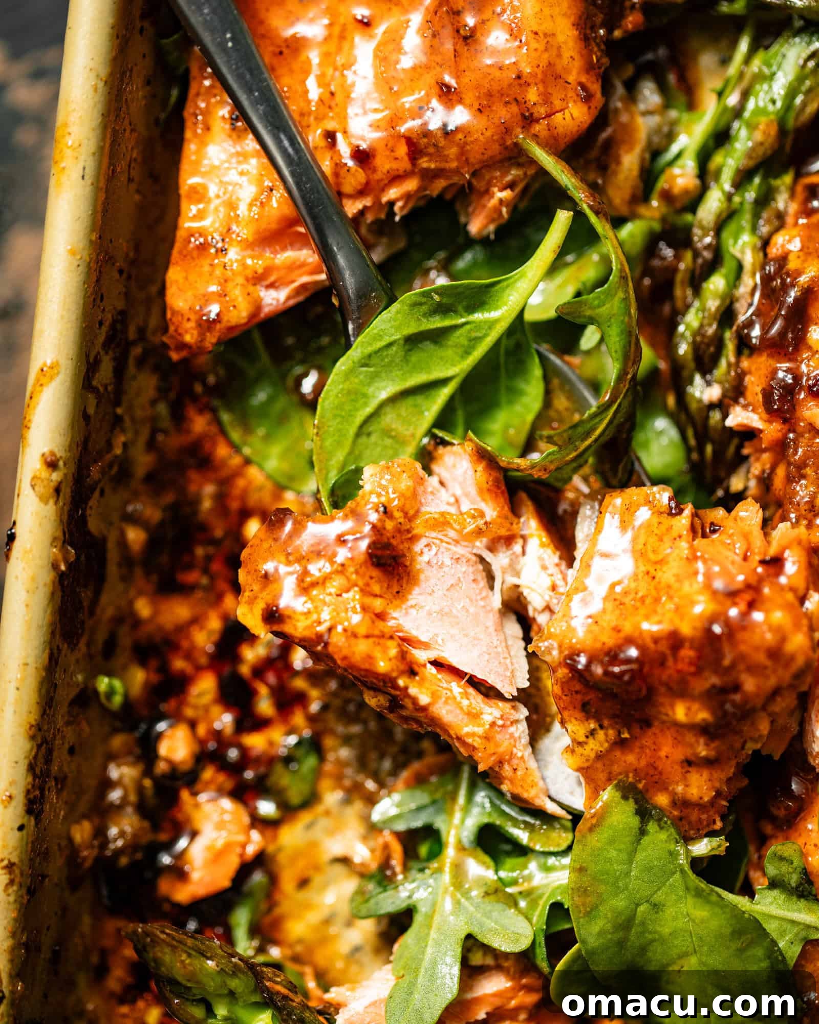 A forkful of Cajun Honey Butter Salmon with fresh basil, showcasing the rich glaze and tender fish.