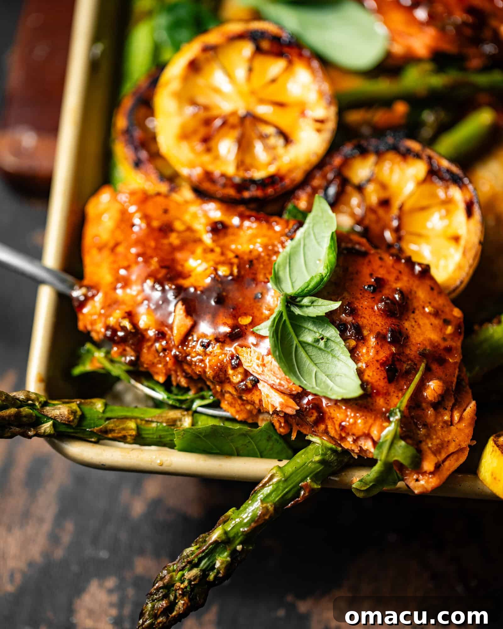 Cajun Honey Butter Salmon on a sheet pan with roasted asparagus, ready to be served, with a fork digging in.