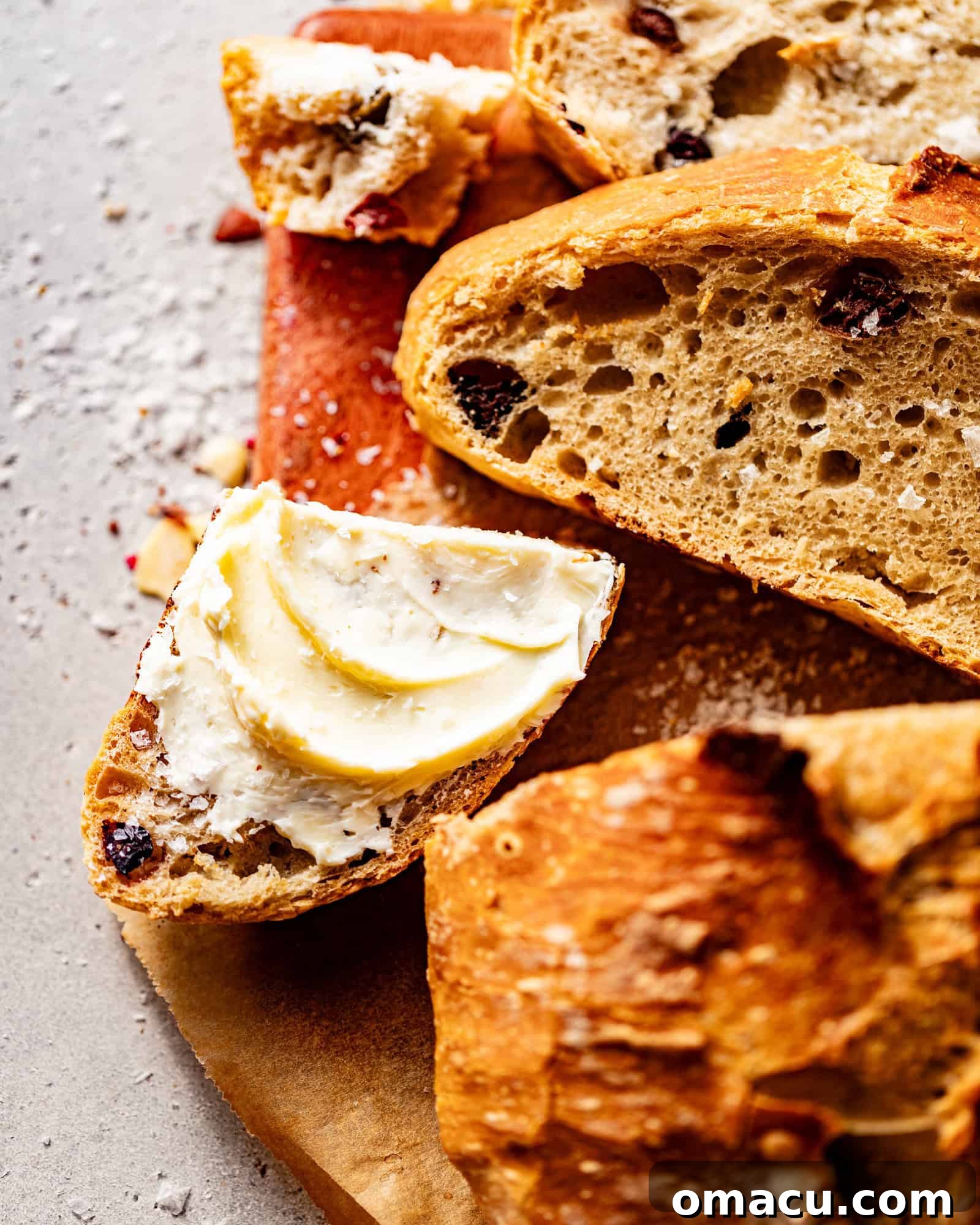 No-knead olive bread cut into small, buttered pieces on a brown serving tray, ready to eat.