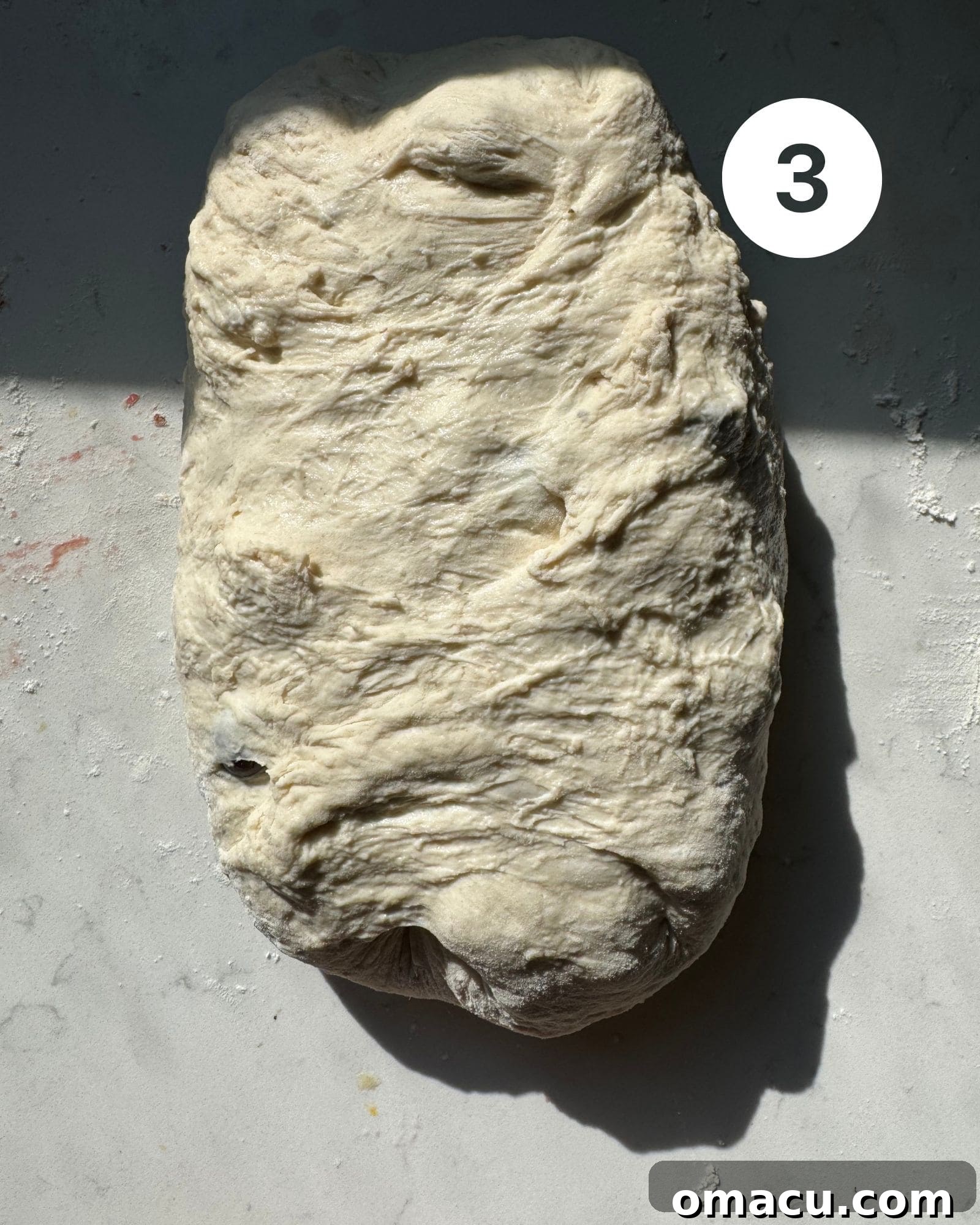Shaped olive bread dough resting on a piece of parchment paper, ready for baking.