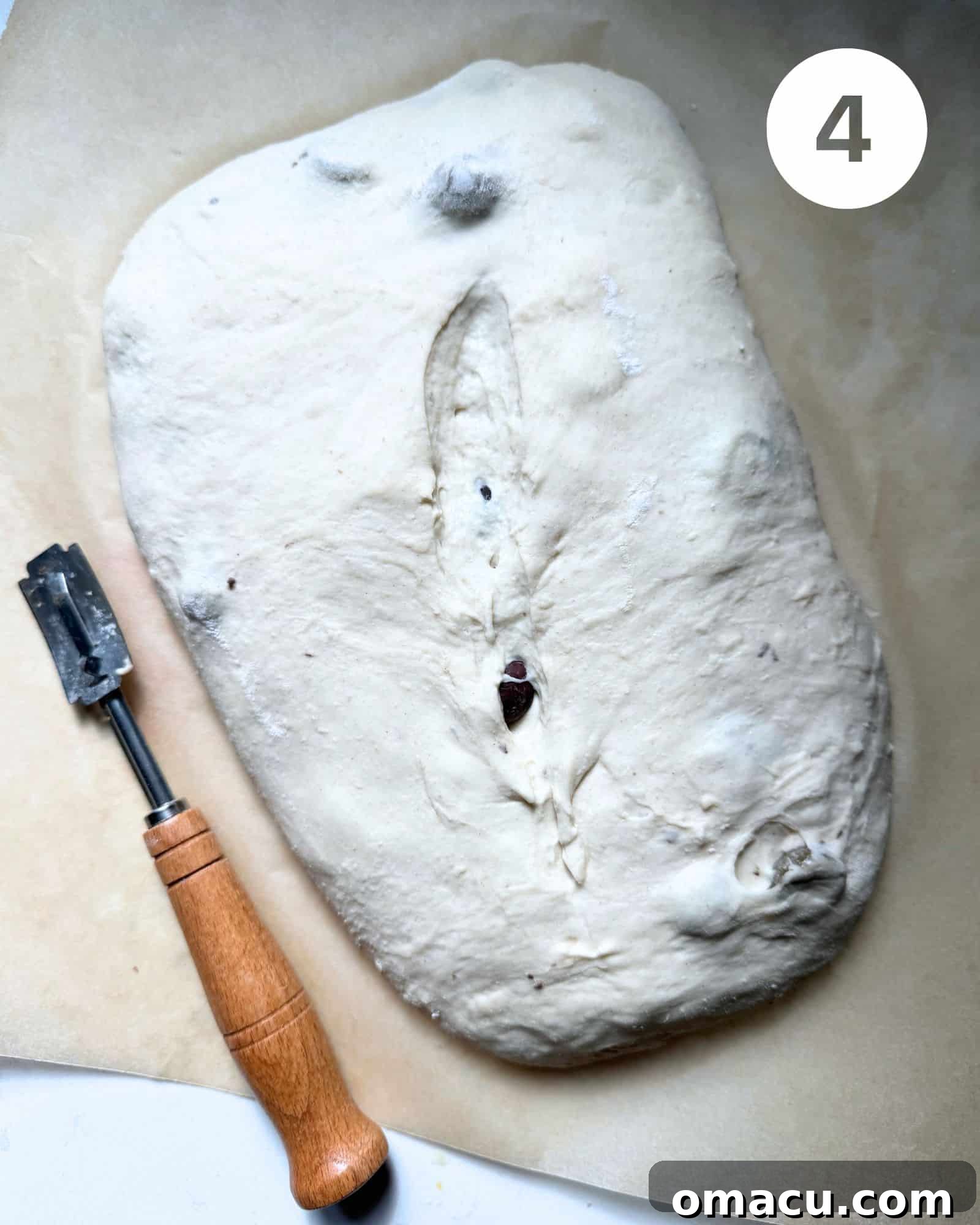Bread dough with three parallel slits made in the top surface using a bread lame, next to the scoring tool.