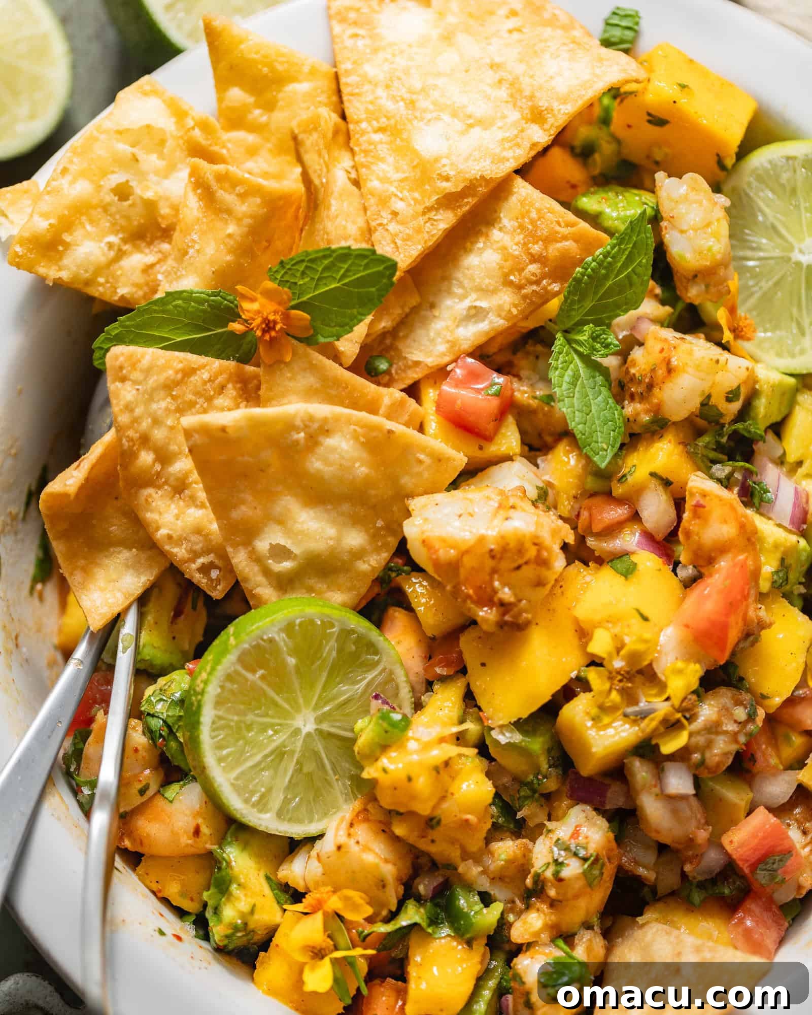 A large serving bowl filled with the colorful mango shrimp salad, garnished with fresh herbs, ready to be served with spoons.