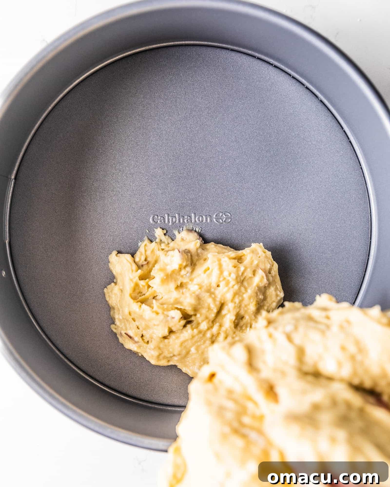 Smooth almond cake batter being carefully poured into a prepared 9-inch springform pan, ready for baking.