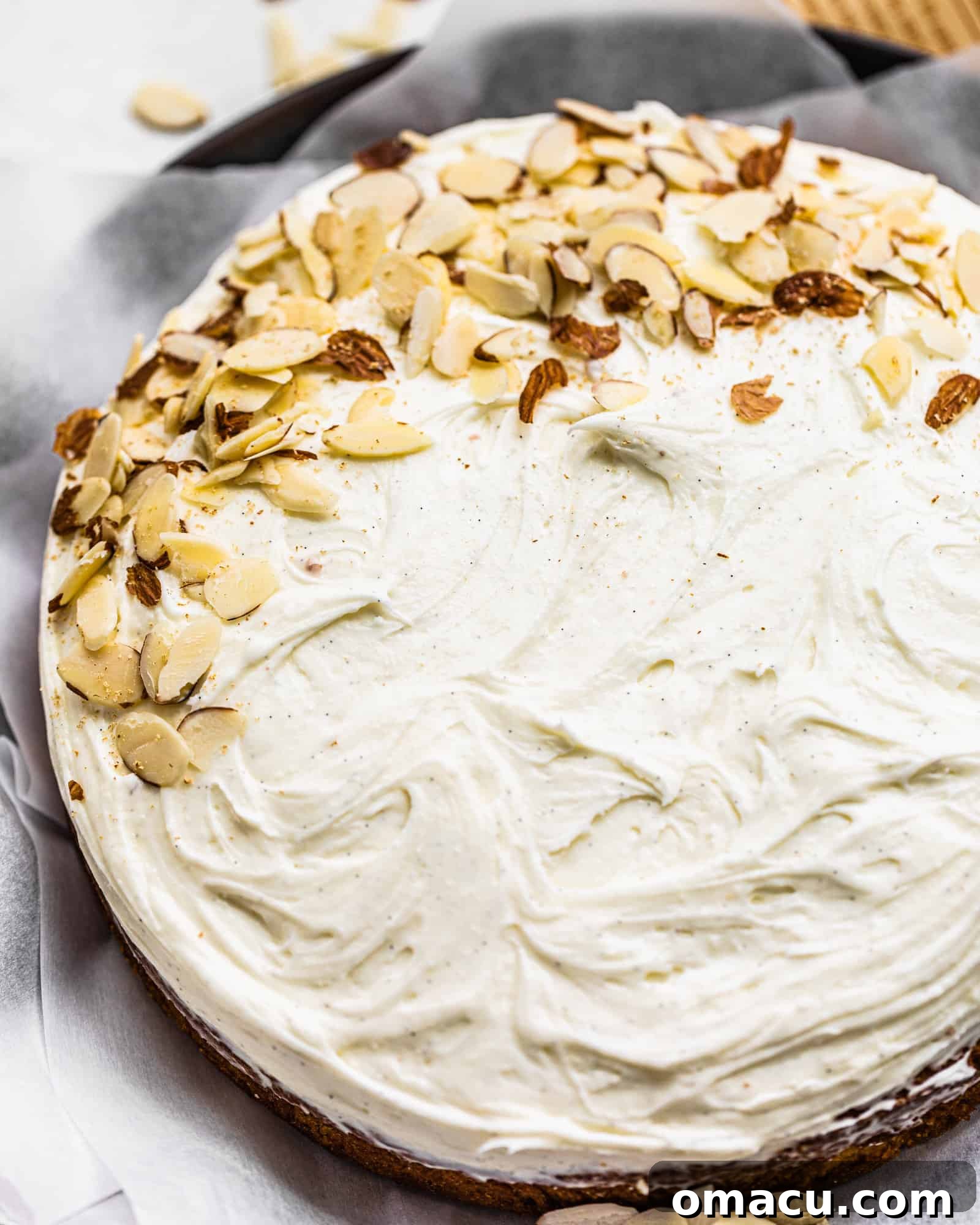 A glorious finished almond cake, generously frosted with whipped mascarpone and elegantly topped with toasted sliced almonds, ready for slicing.
