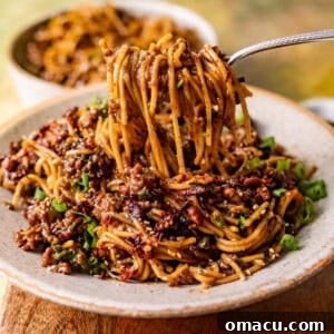 saucy mongolian ground beef noodles in a bowl with a fork pulling the noodles out of the bowl.