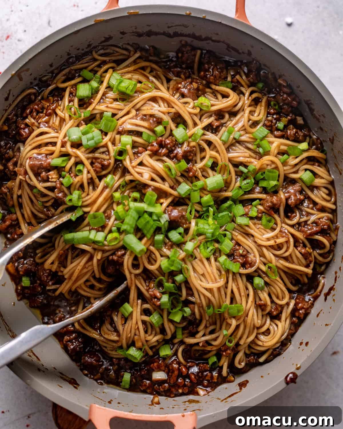 noodles added to the ground beef mixture with scallions and sesame seeds on top.