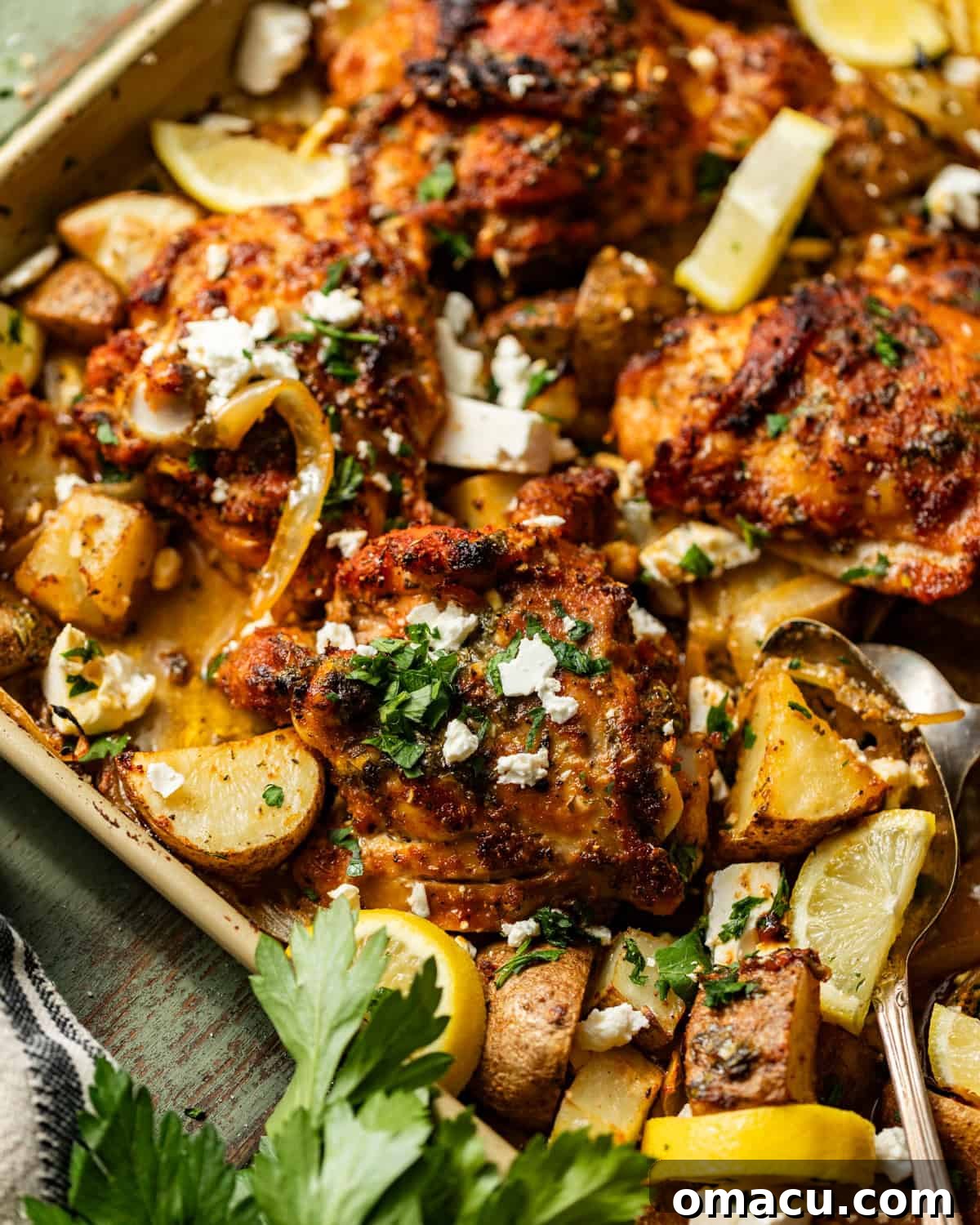 sheet pan chicken thighs and potatoes topped with parsley and feta.