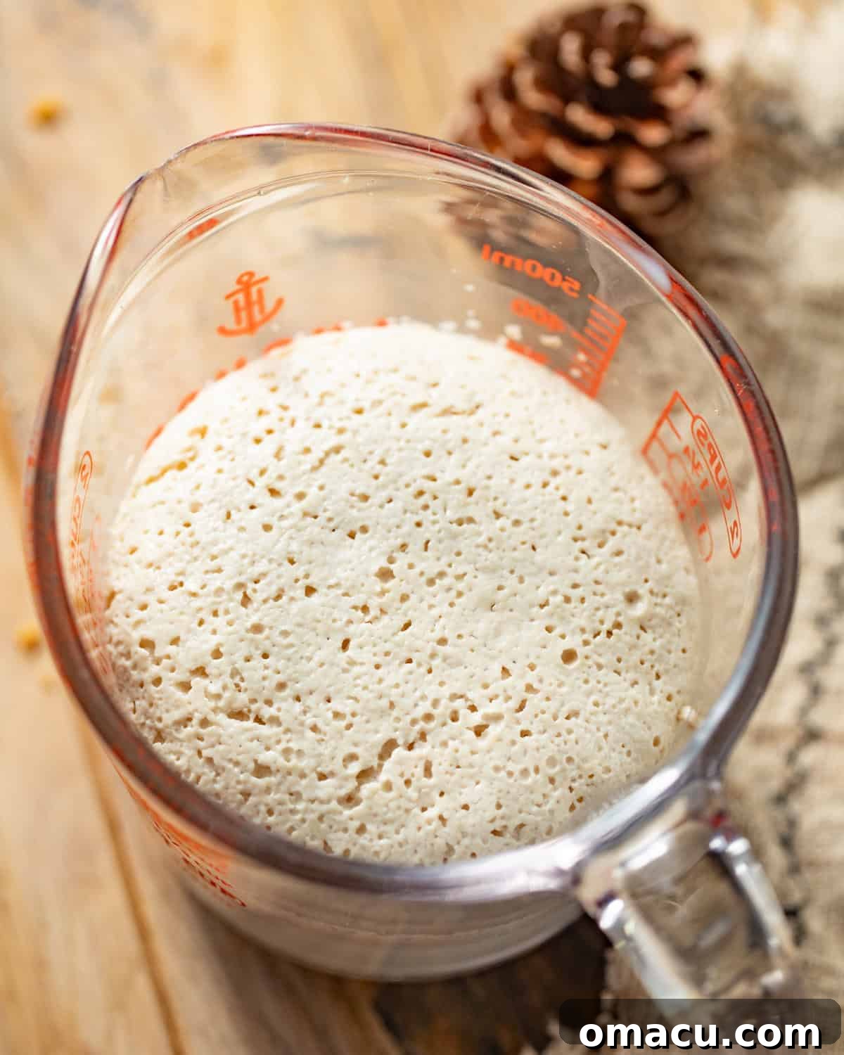 Bloomed active dry yeast in a measuring cup, mixed with warm water, evaporated milk, and sugar, alongside other wet ingredients.