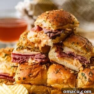 Reuben sliders stacked enticingly on top of each other, served alongside a bowl of crispy potato chips, illustrating a perfect party snack or quick meal.