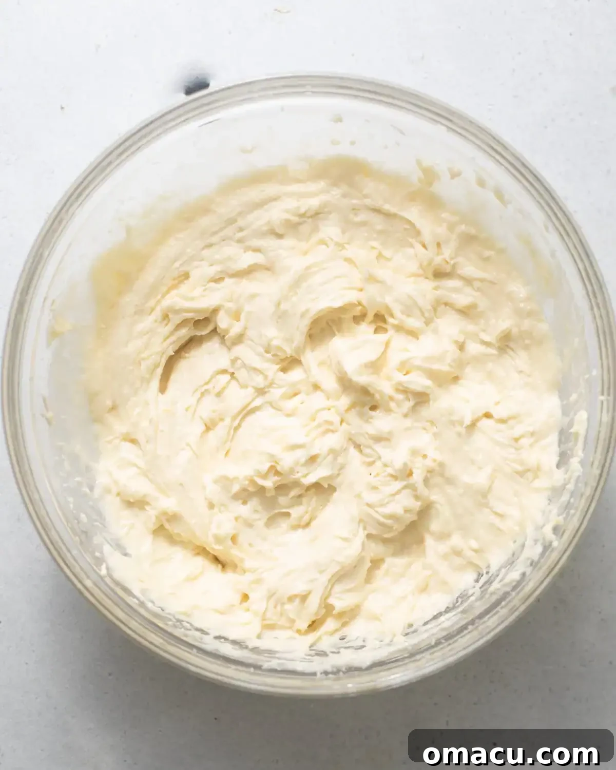Room temperature butter, vegetable oil, granulated sugar, and brown sugar are being creamed together in a large mixing bowl, showing a pale and fluffy texture.