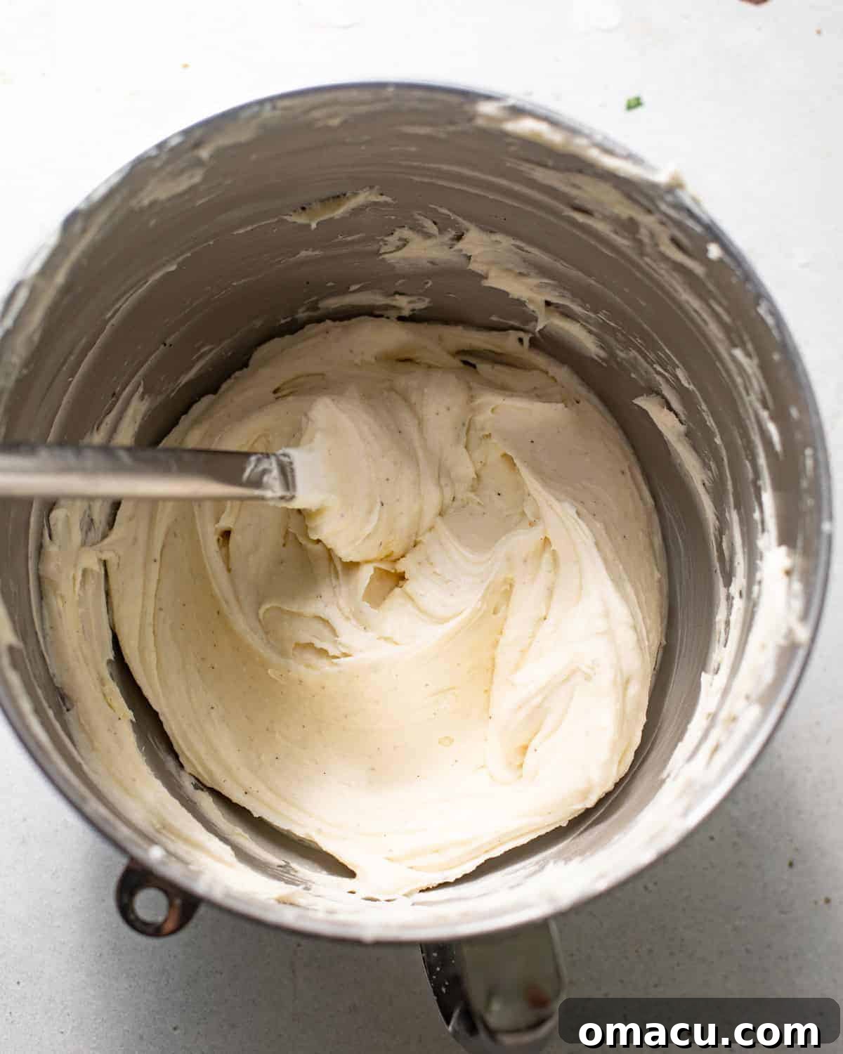 A bowl of creamy, tangy cream cheese frosting, perfectly mixed and ready to spread on the cooled red velvet cake.