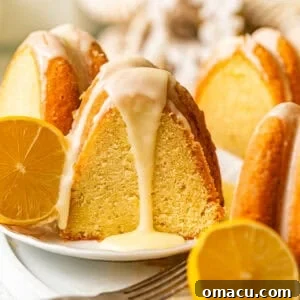 A slice of lemon ricotta pound cake on a plate with sliced lemons and lemon glaze being poured on top.