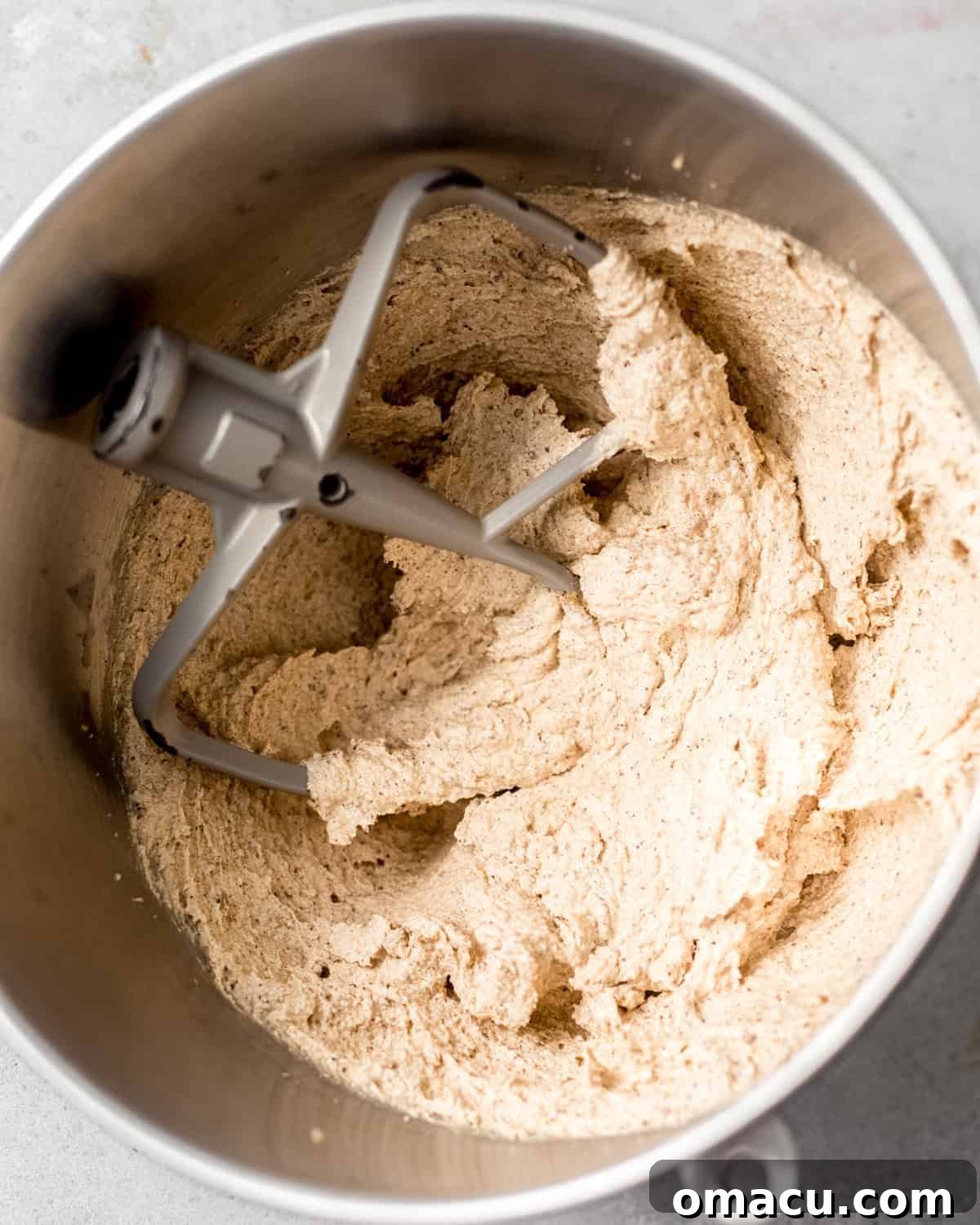 Close-up of lemon zest being vigorously rubbed into granulated sugar in a mixing bowl, prior to creaming with butter and oil for the cake batter.
