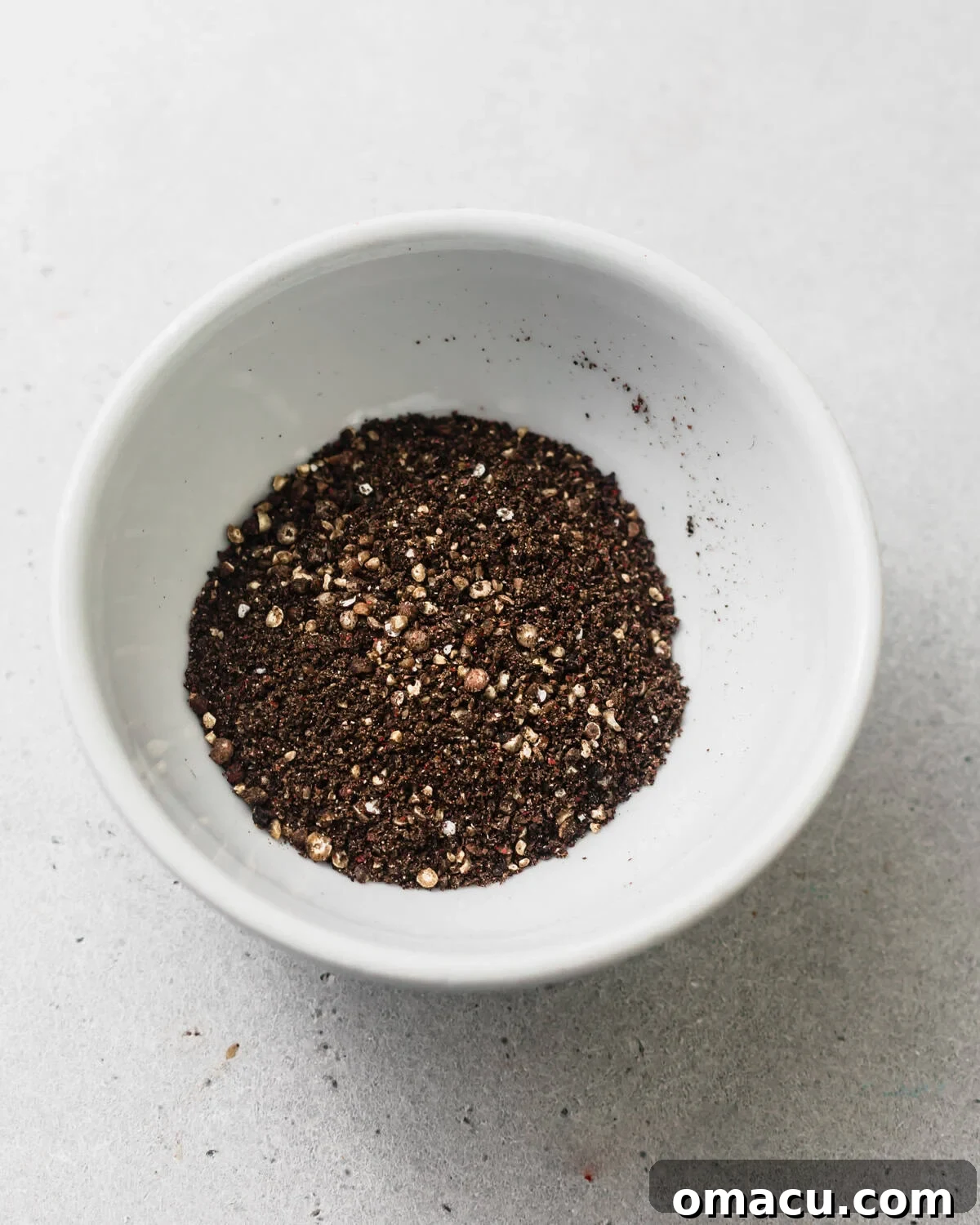 Crushed peppercorns in a bowl, showing the coarse texture ready for coating the steak.