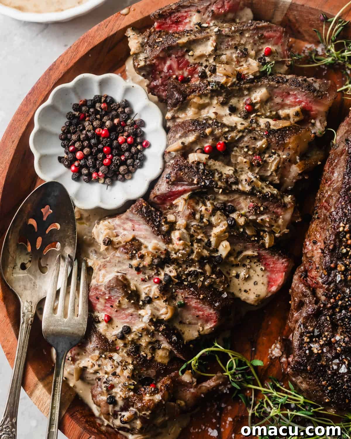 Sliced steak on a serving plate with peppercorn sauce generously poured on top, ready to enjoy.