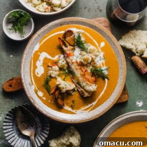 A bowl of creamy lobster bisque, beautifully garnished with fresh lobster pieces, a delicate cream drizzle, and a sprig of fresh dill, showcasing its elegance and inviting texture.