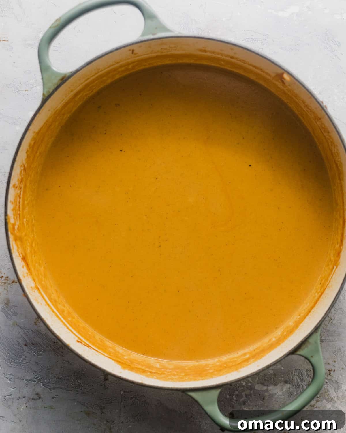The finished lobster bisque simmering gently in a large pot, rich and creamy, ready for final garnishes and serving.