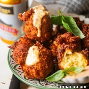 Crispy crab beignets on a plate with fresh parsley and remoulade sauce drizzled on top, ready to be enjoyed.