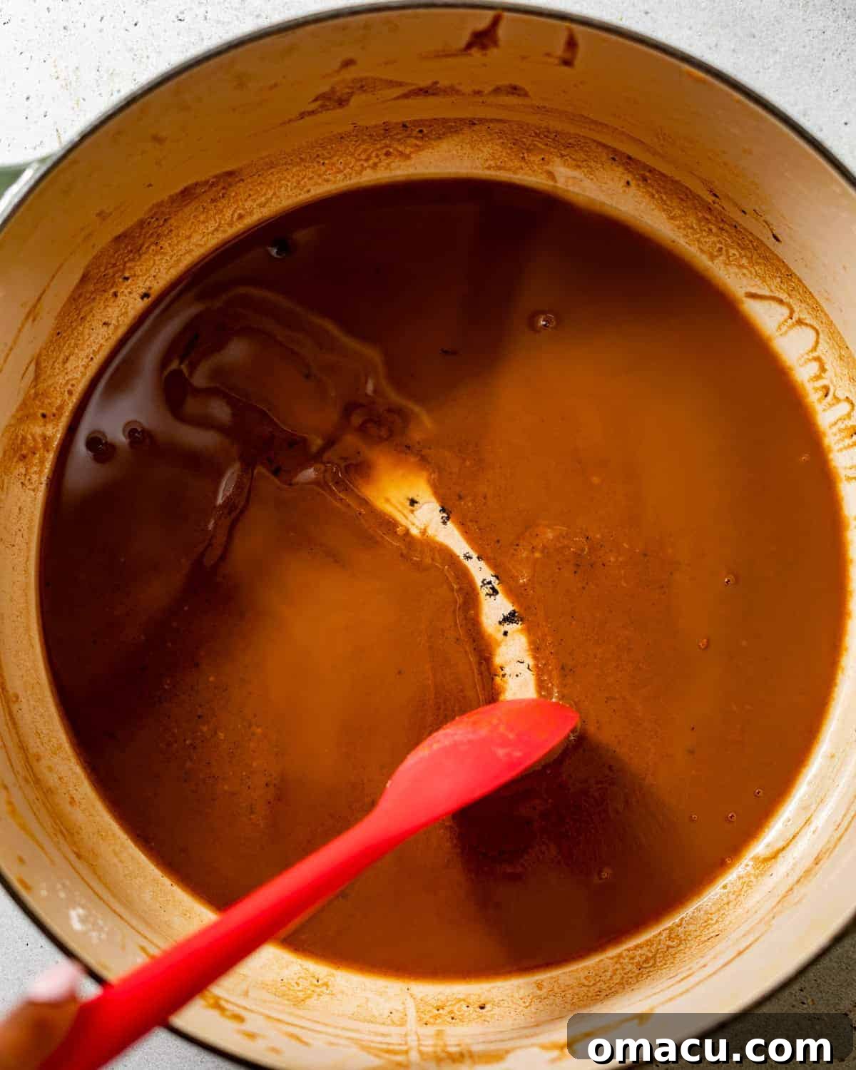 A rich, dark chocolate-colored roux simmering gently in a large pot, indicating perfect development of flavor.