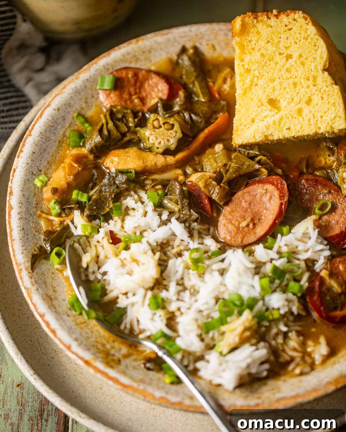 A vibrant bowl of Southern Gumbo Greens, steaming gently, served alongside a neat pile of white rice and a wedge of cornbread, ready to be enjoyed.