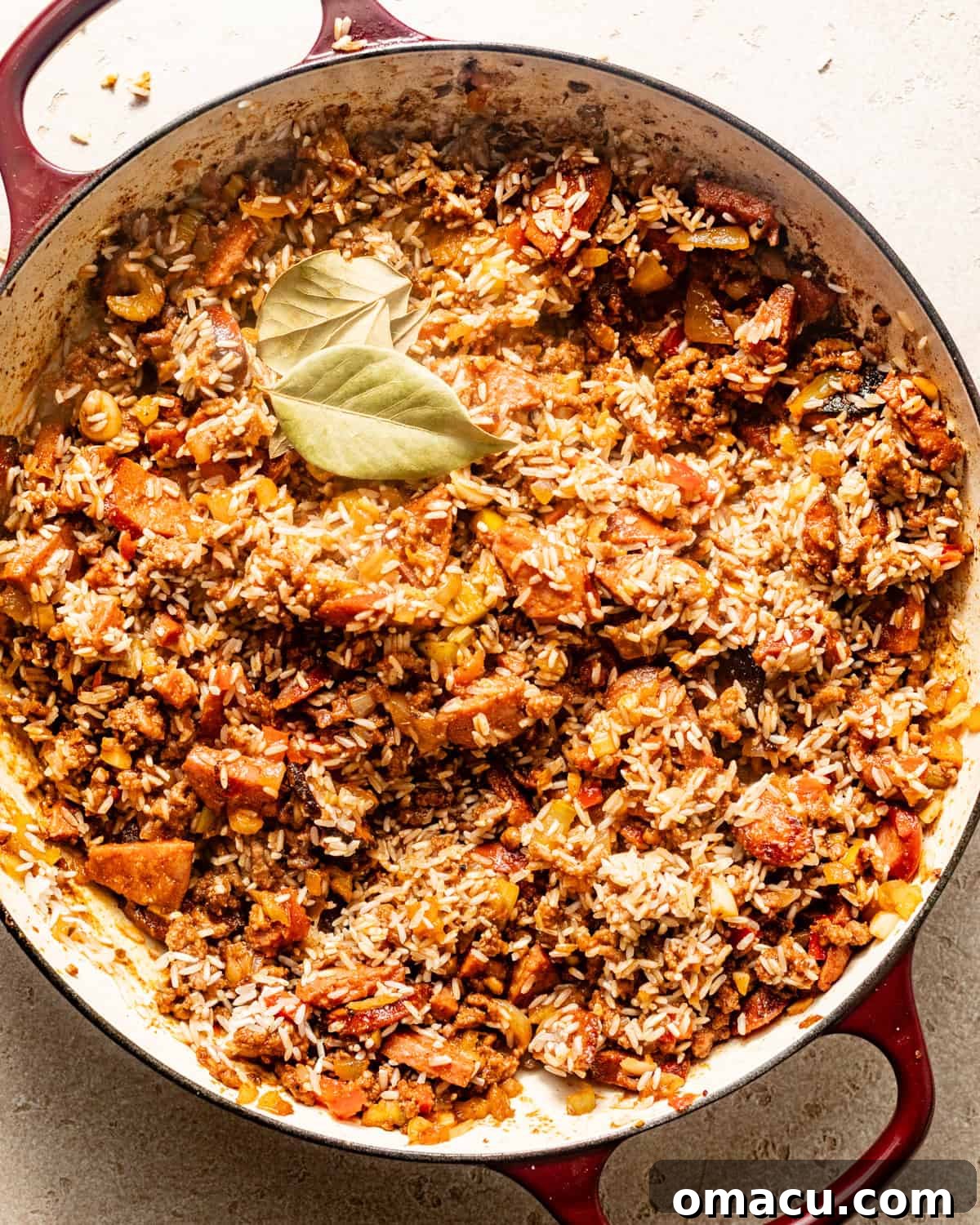 dirty rice in a pot with bay leaves, simmering in chicken broth.