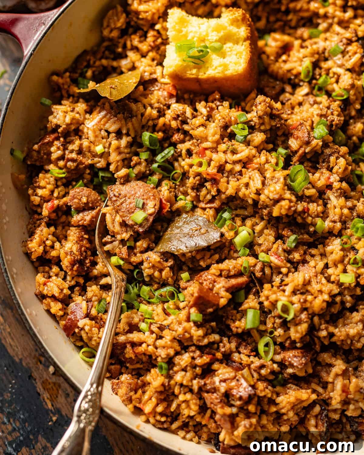 up close photo of louisiana dirty rice in a skillet with a serving spoon. 