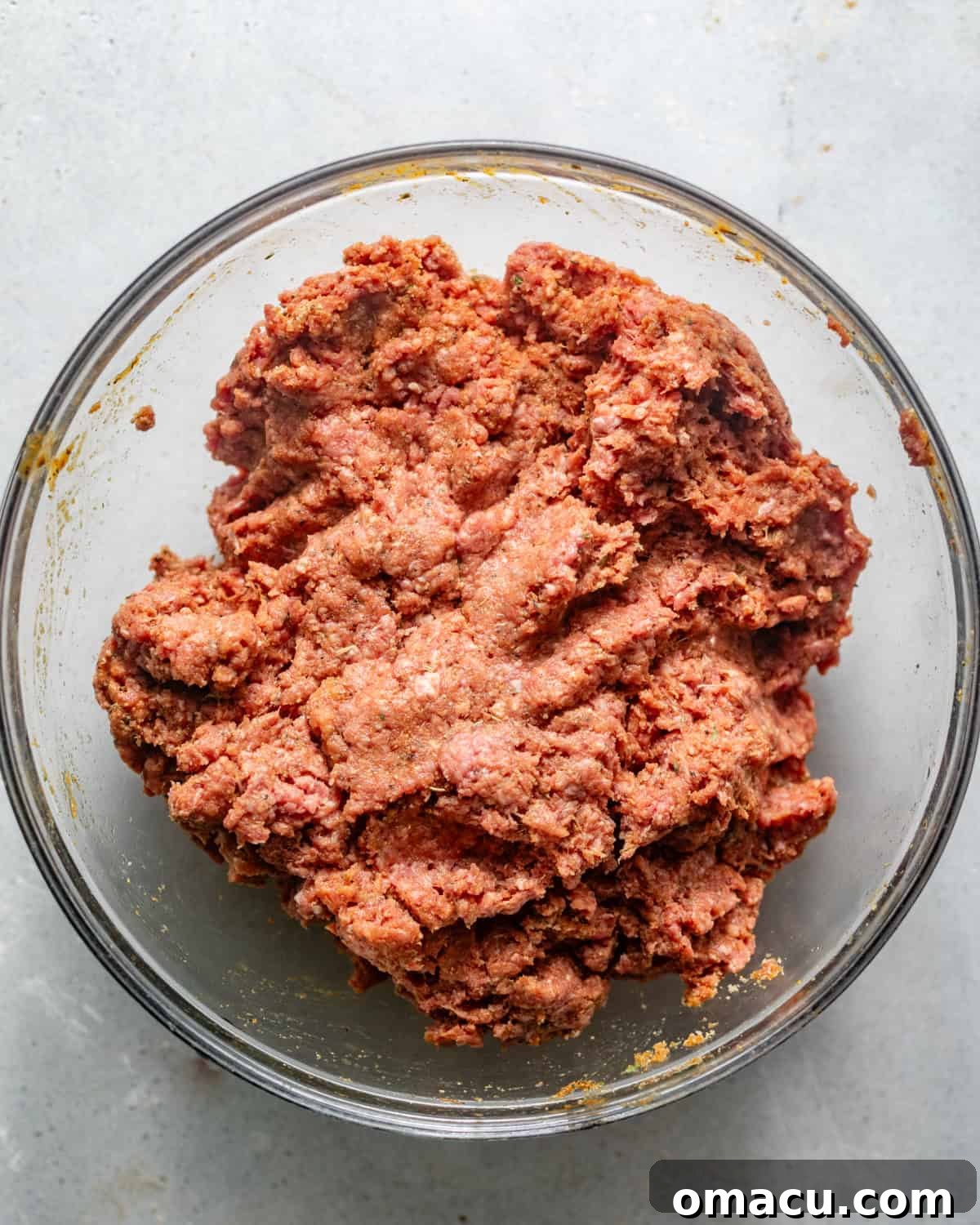 Close-up of ground beef mixture in a mixing bowl, showing the texture and even distribution of ingredients.