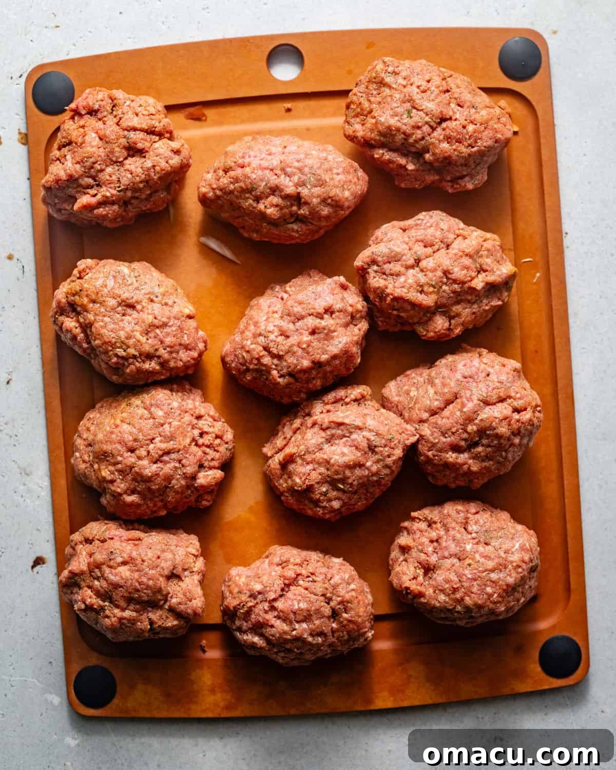 Four raw hamburger steak patties, perfectly shaped and ready for searing, arranged on a cutting board.