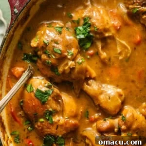 smothered chicken in a pot with a serving spoon with fresh parsley garnish on top.