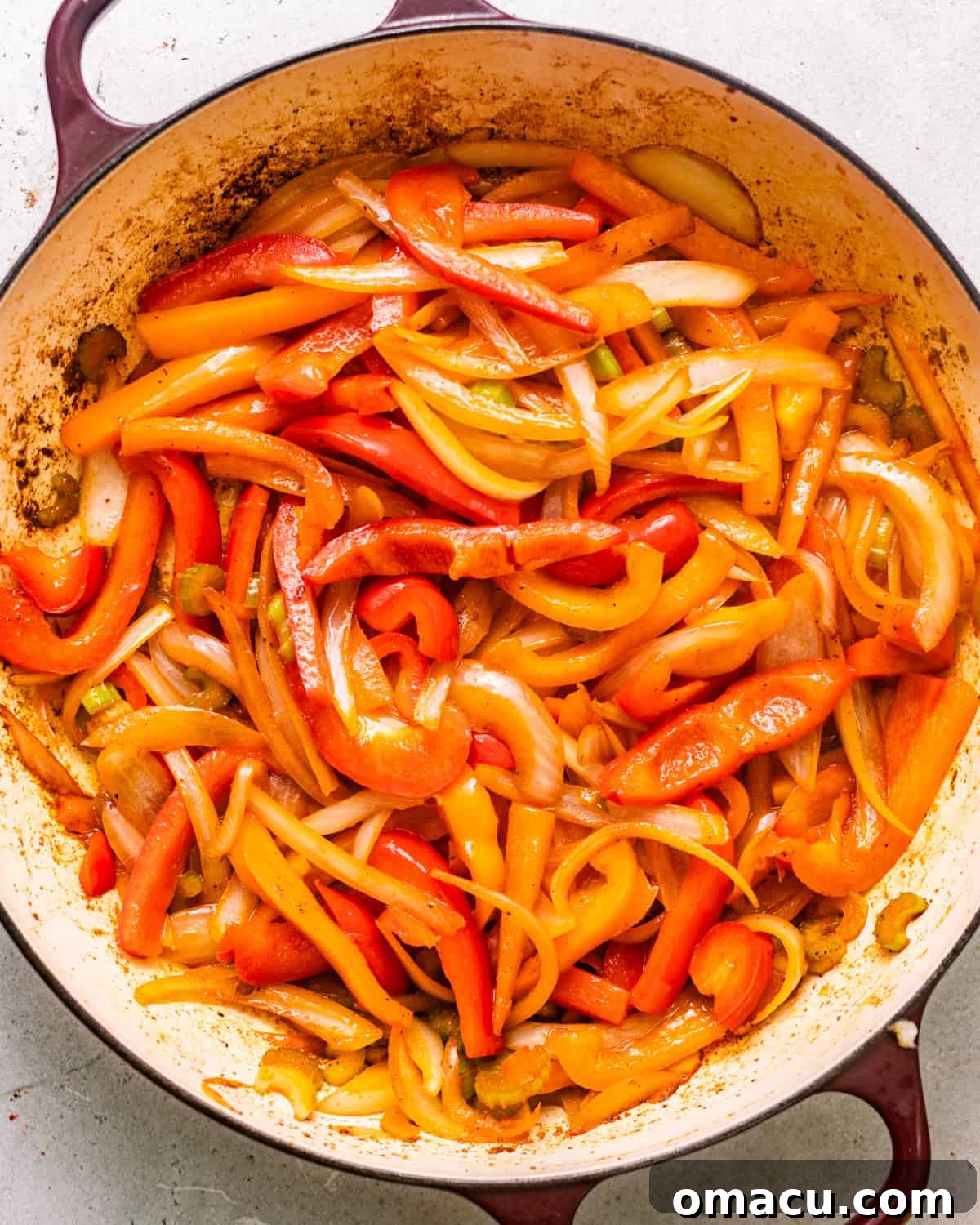 sauteed onions, bell peppers, celery, and garlic in a pot with seasonings.