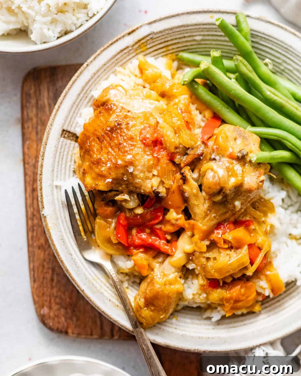 smothered chicken on plate with rice and green beans. 
