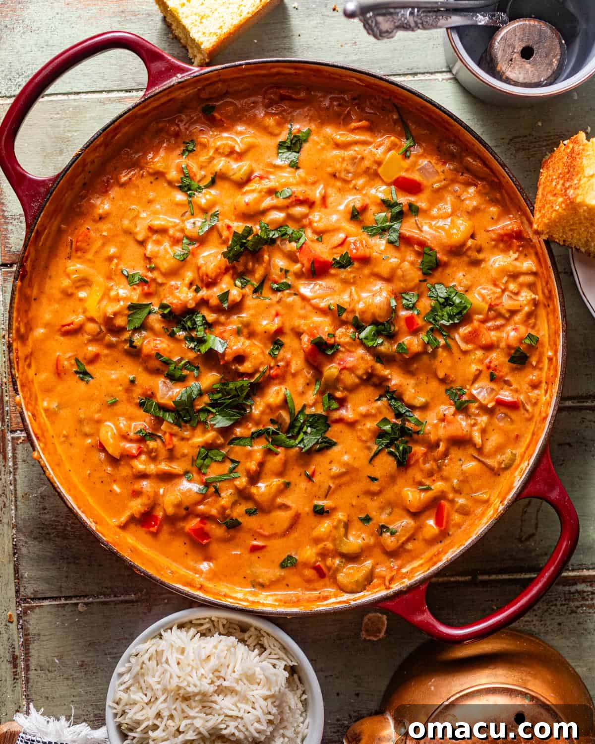 Finished crawfish étouffée in a large pot, generously garnished with fresh chopped parsley, ready to be served.