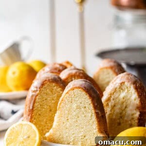 sliced lemon buttermilk pound cake on a plate with sliced lemons, main recipe image.
