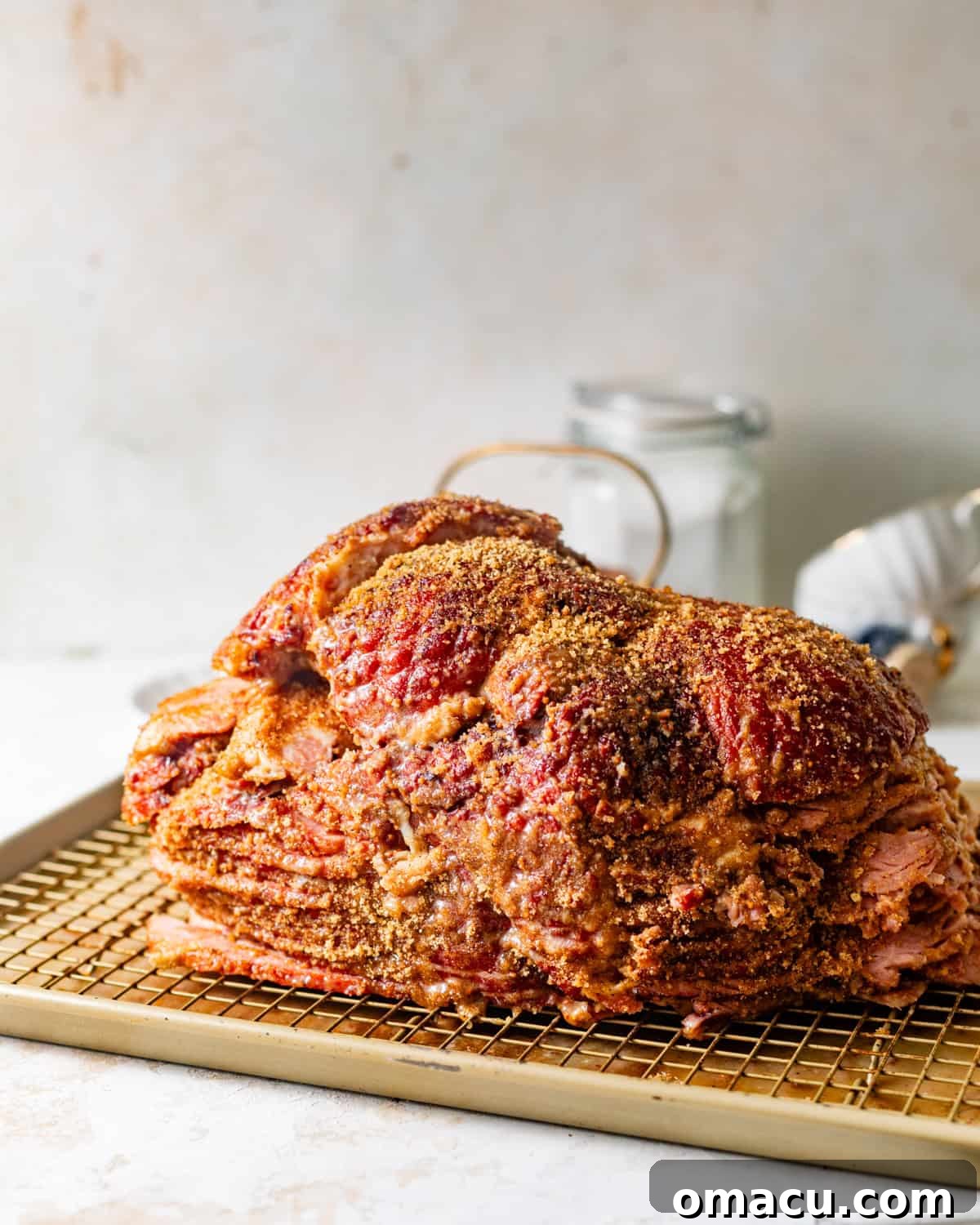 The ham is thoroughly coated in the sweet honey Dijon glaze and rich brown sugar seasonings, resting on a wire rack, ready for its initial bake.