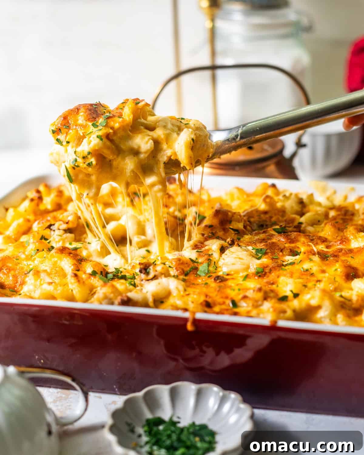 Seafood Mac and Cheese being scooped from a baking dish, showcasing a rich cheese pull and golden crust.