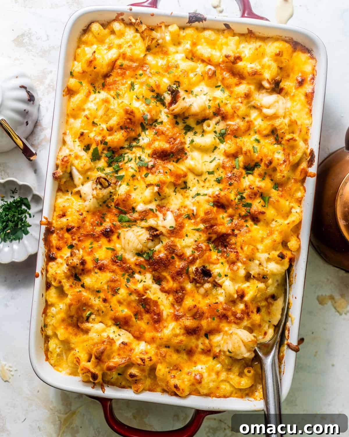 Overhead photo of seafood mac and cheese being layered in a baking dish before baking.