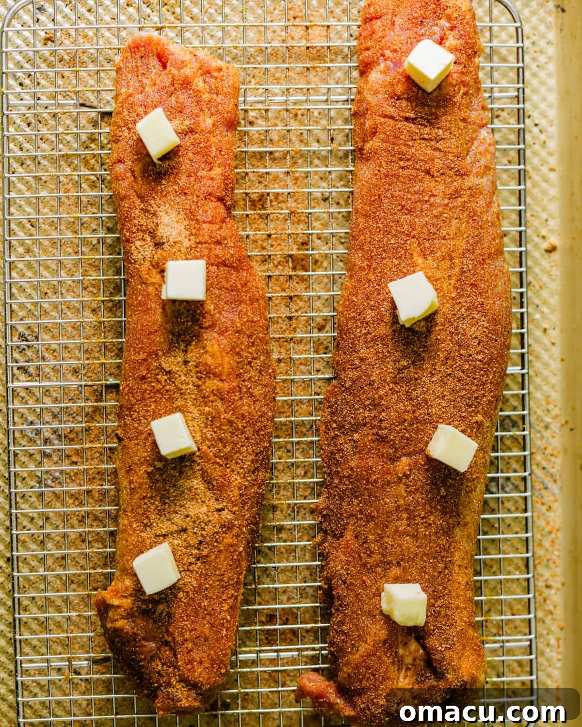 Seasoned pork tenderloin baking uncovered on a wire rack, with butter melting and basting the meat as it roasts.