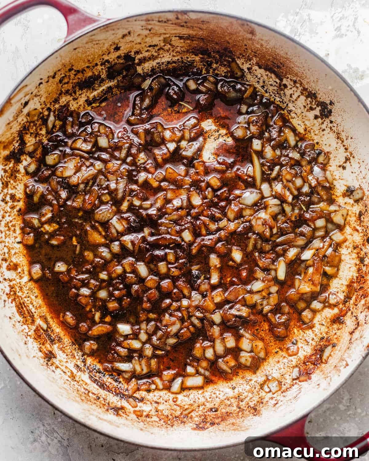Sautéing diced shallots and minced garlic in a skillet with butter and pan drippings, forming the aromatic base for the Cajun cream sauce.