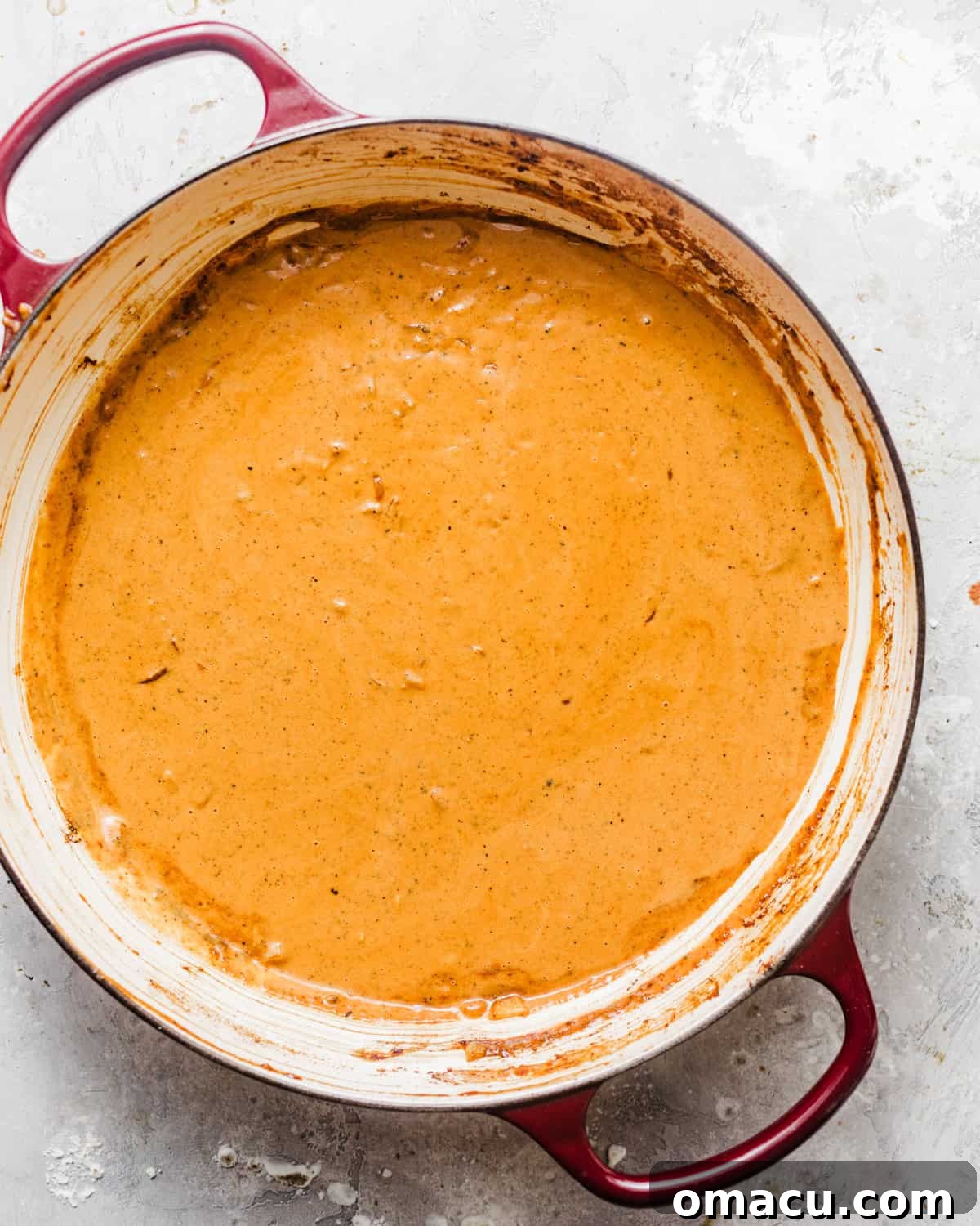 The creamy Cajun sauce thickening in a skillet on the stovetop, with Parmesan cheese and a squeeze of fresh lemon juice being added.