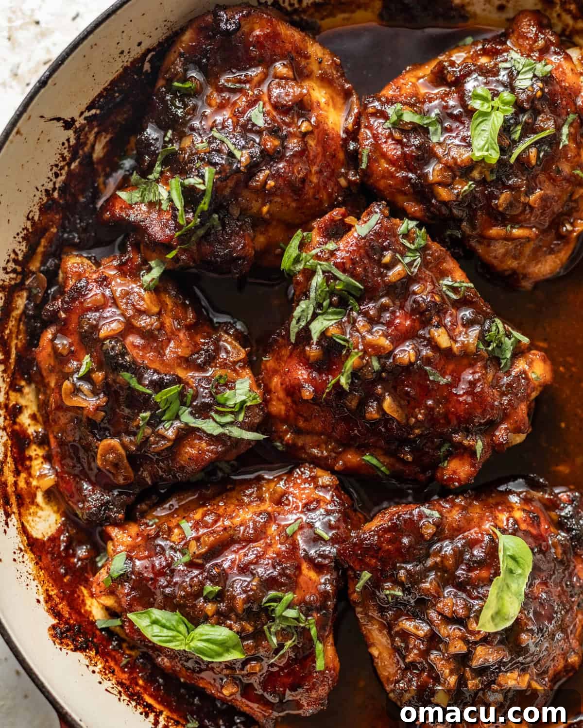 Honey garlic chicken thighs in a skillet topped with a sticky honey garlic glaze and chopped parsley, ready to be served.