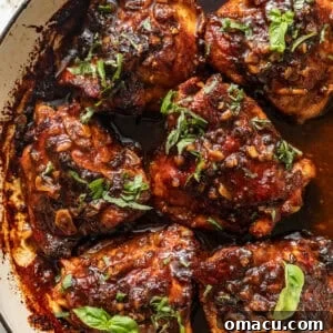 honey garlic chicken thighs in a skillet topped with a sticky honey garlic glaze and chopped parsley.