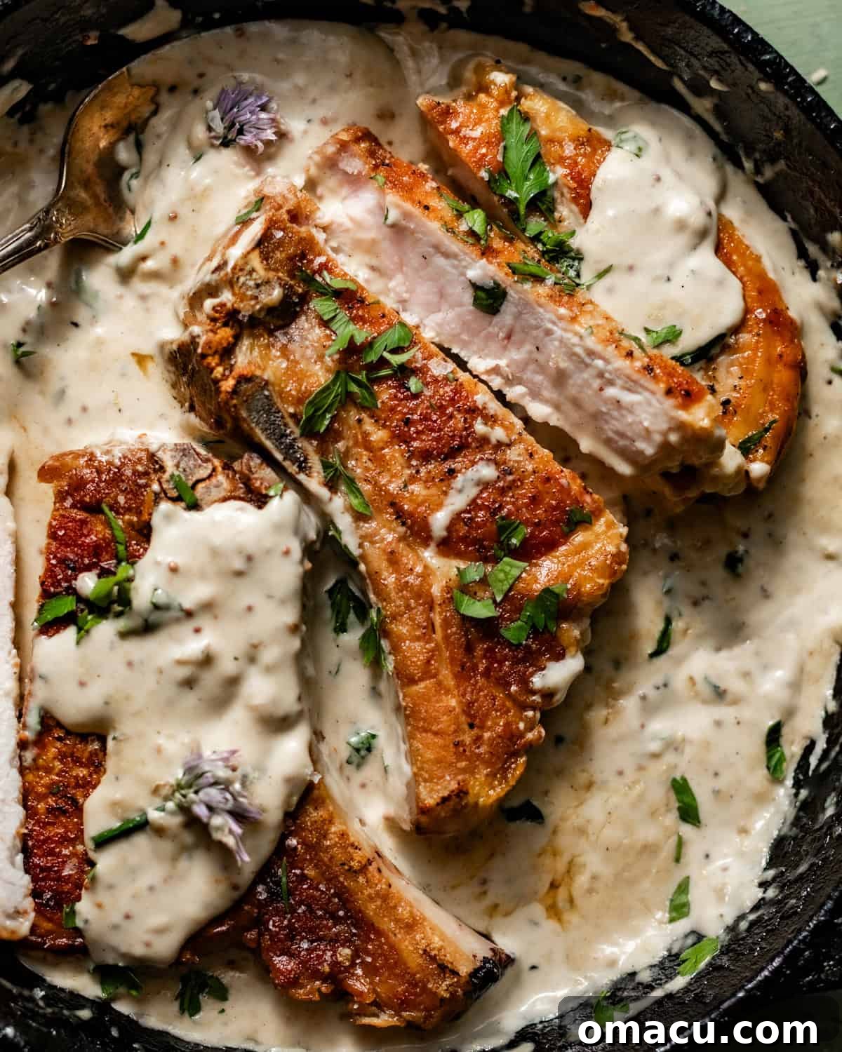 sliced pork chops in a skillet covered in creamy garlic butter sauce.