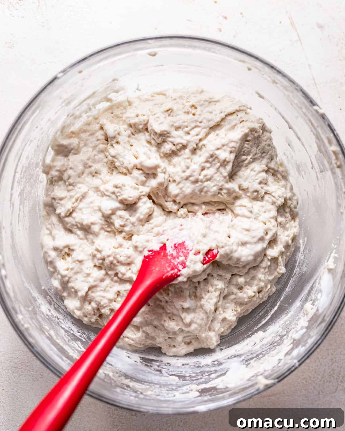 Biscuit dough mixed together in a large bowl, showing its lumpy texture, ready to be transferred to the baking dish.