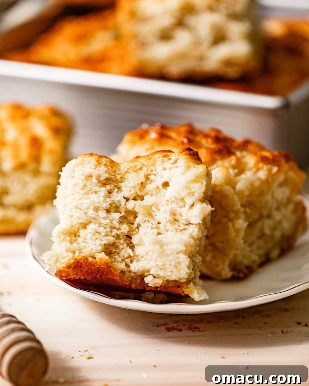 A single butter swim biscuit, artfully cut in half to reveal its incredibly soft, fluffy interior, resting on a small plate.