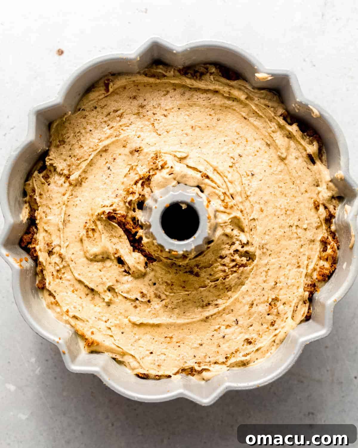 Smooth peanut butter pound cake batter meticulously poured into a greased and floured bundt pan, ready for baking.
