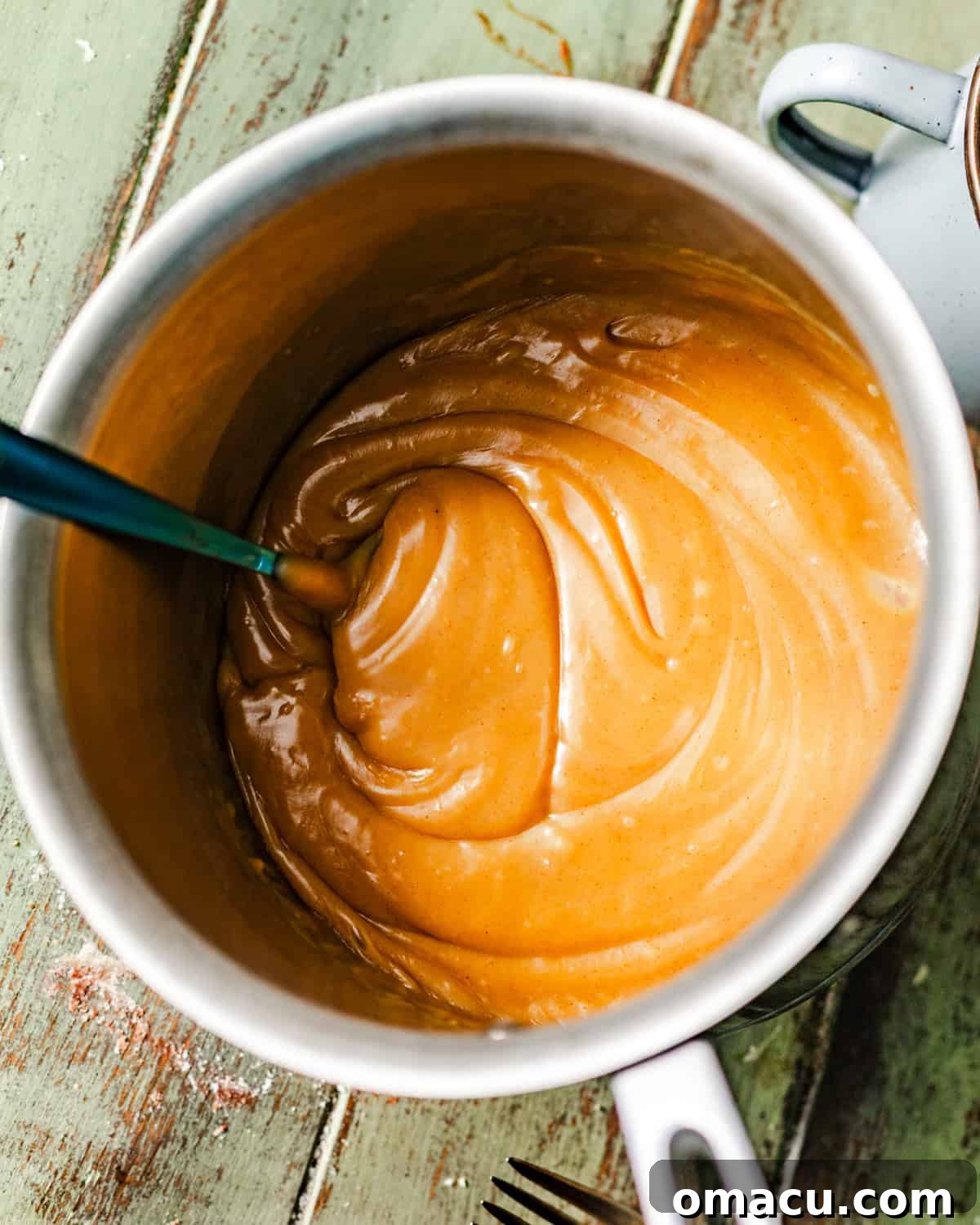 Creamy peanut butter fudge frosting simmering gently in a saucepan, showing its smooth and luscious texture.