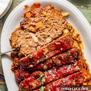 sliced bbq meatloaf on a serving plate garnished with fresh parsley.