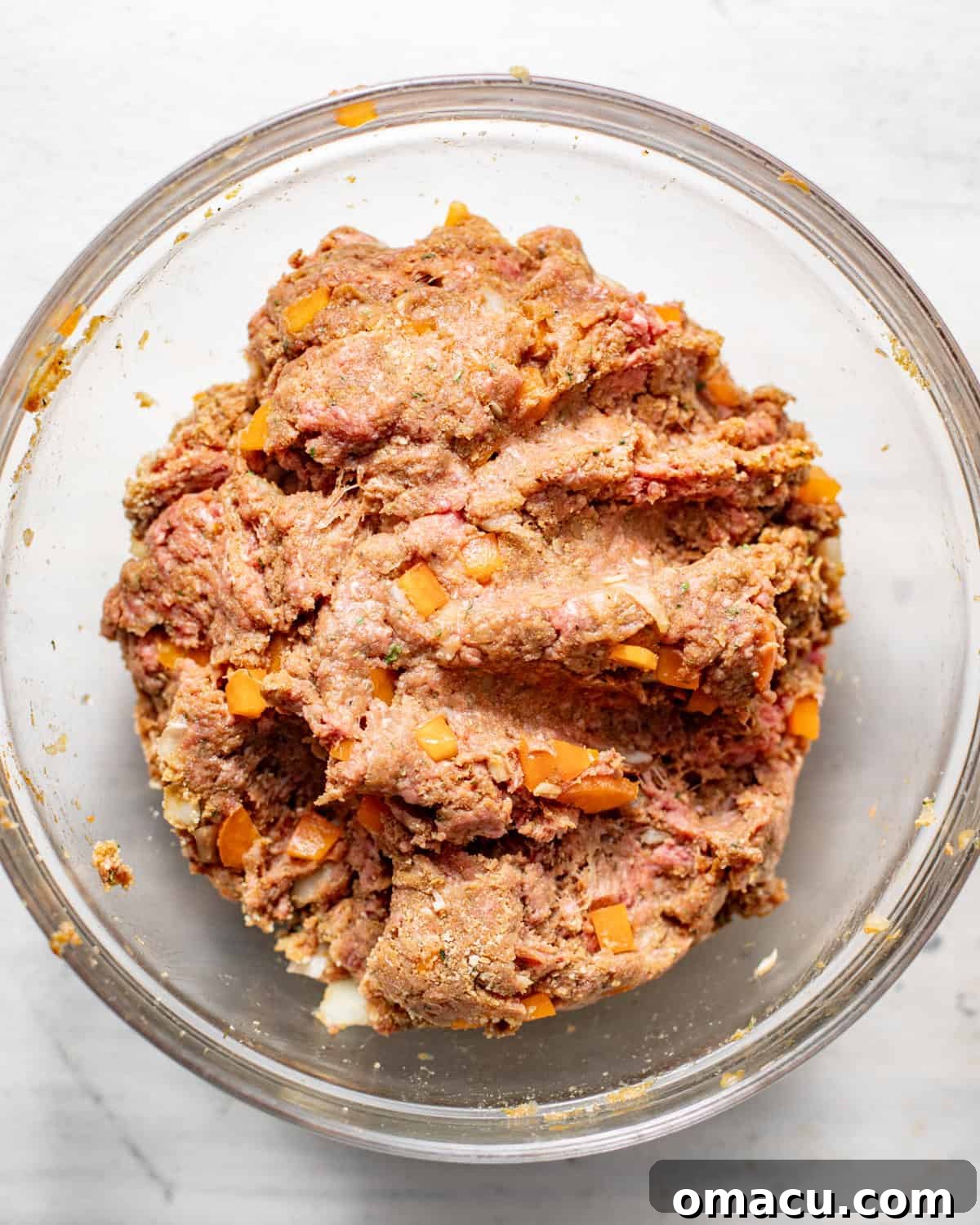 ground beef in a bowl with breadcrumbs, bbq sauce, ketchup, seasonings, and eggs all mixed together.