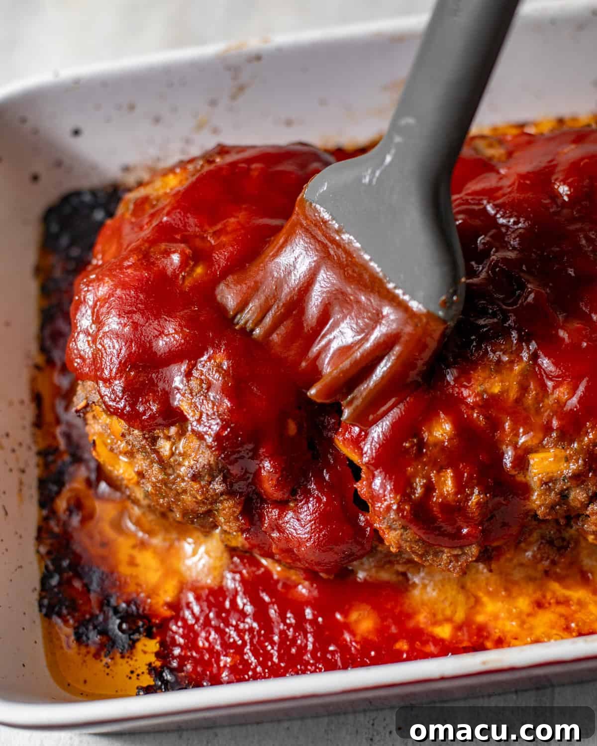 a bbq brush brushing the bbq glaze on top of the meatloaf.